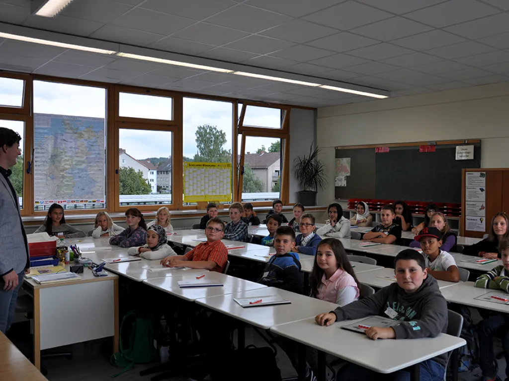 Kinder sitzen im Klassenraum an ihren Plätzen.